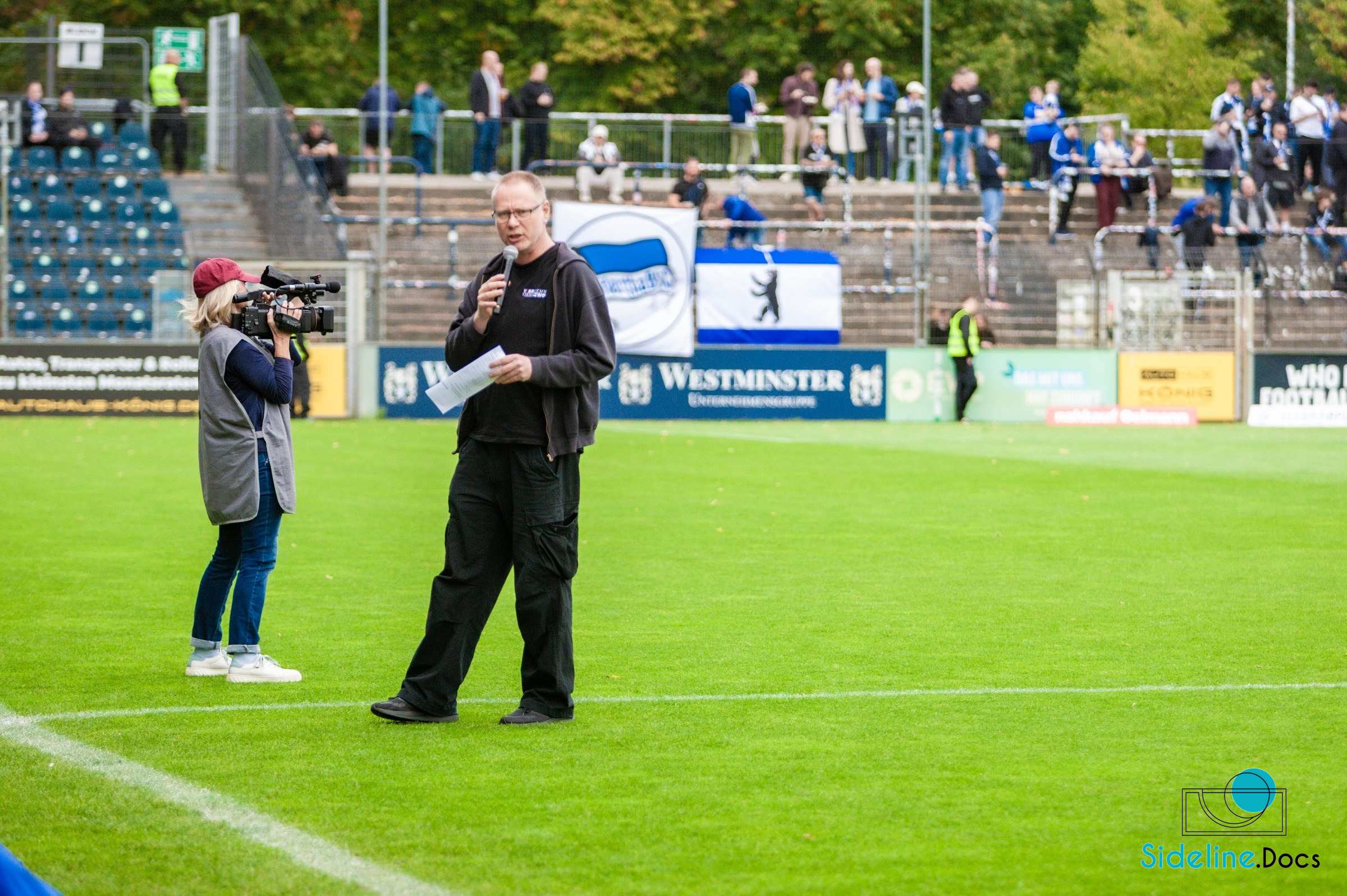 Stadium announcer on the pitch in front of a TV camera