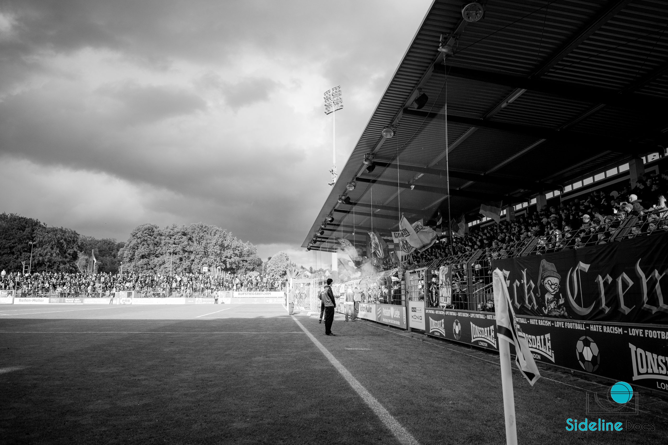 Corner flag toward the covered stand, Eck Crew banner and rising smoke