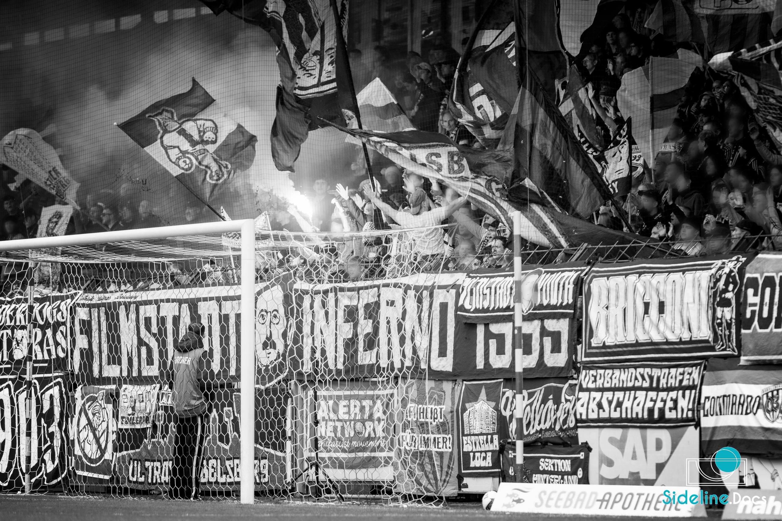 Home curve behind the goal net, Filmstadt Inferno banners and a flare