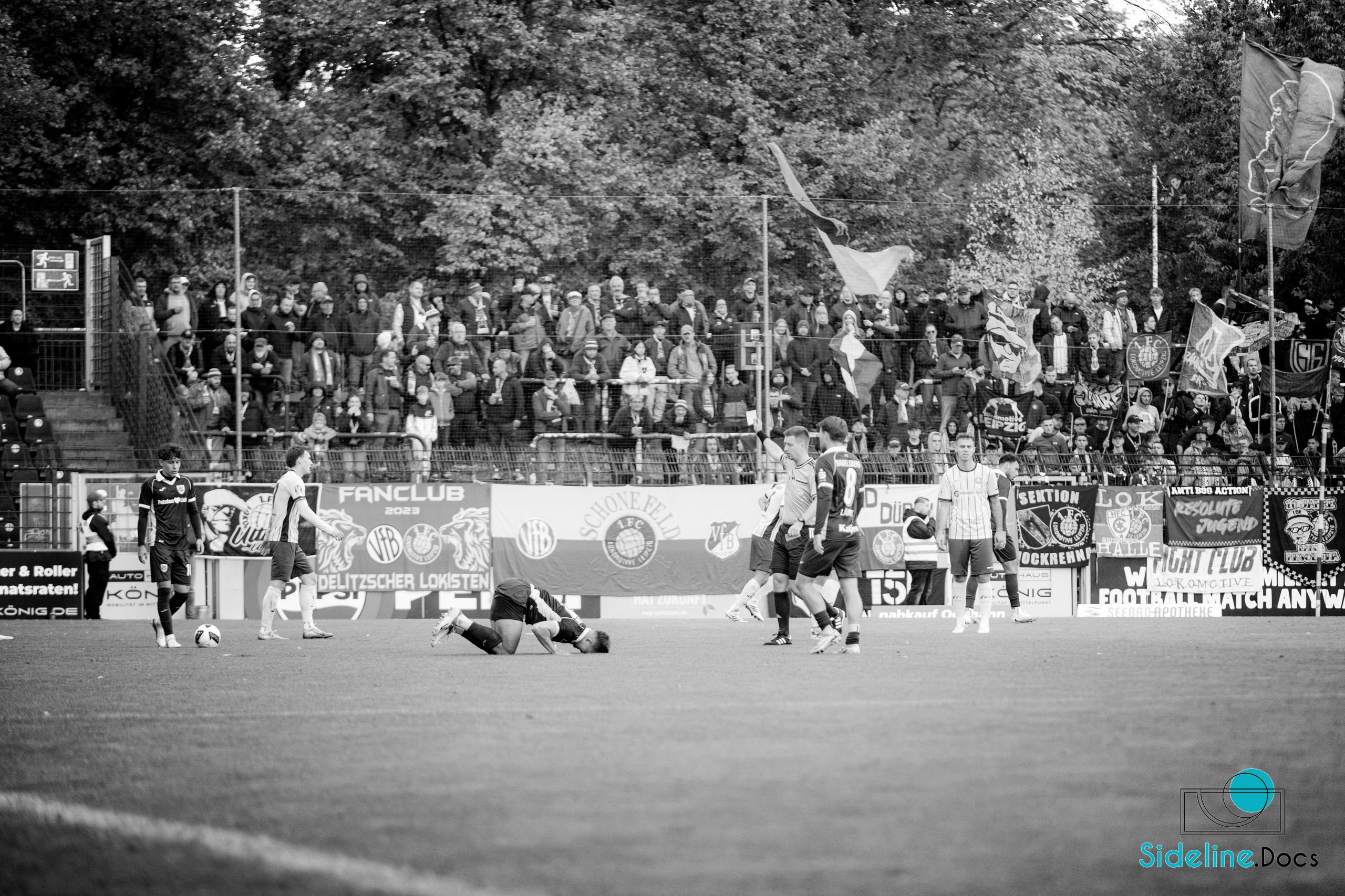Player kneeling on the pitch in front of the Lok away banners