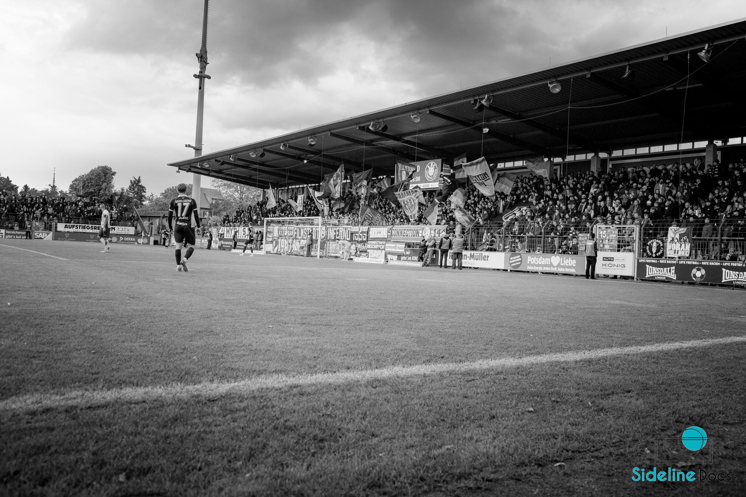 Player walking toward the covered stand while flags move in the block